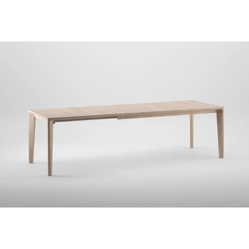 The HANNY Extension Table by Artisan is a minimalist wooden dining table crafted from eco-friendly materials, featuring a light natural finish with four slender legs, clean lines, and a rectangular shape against a plain white background.