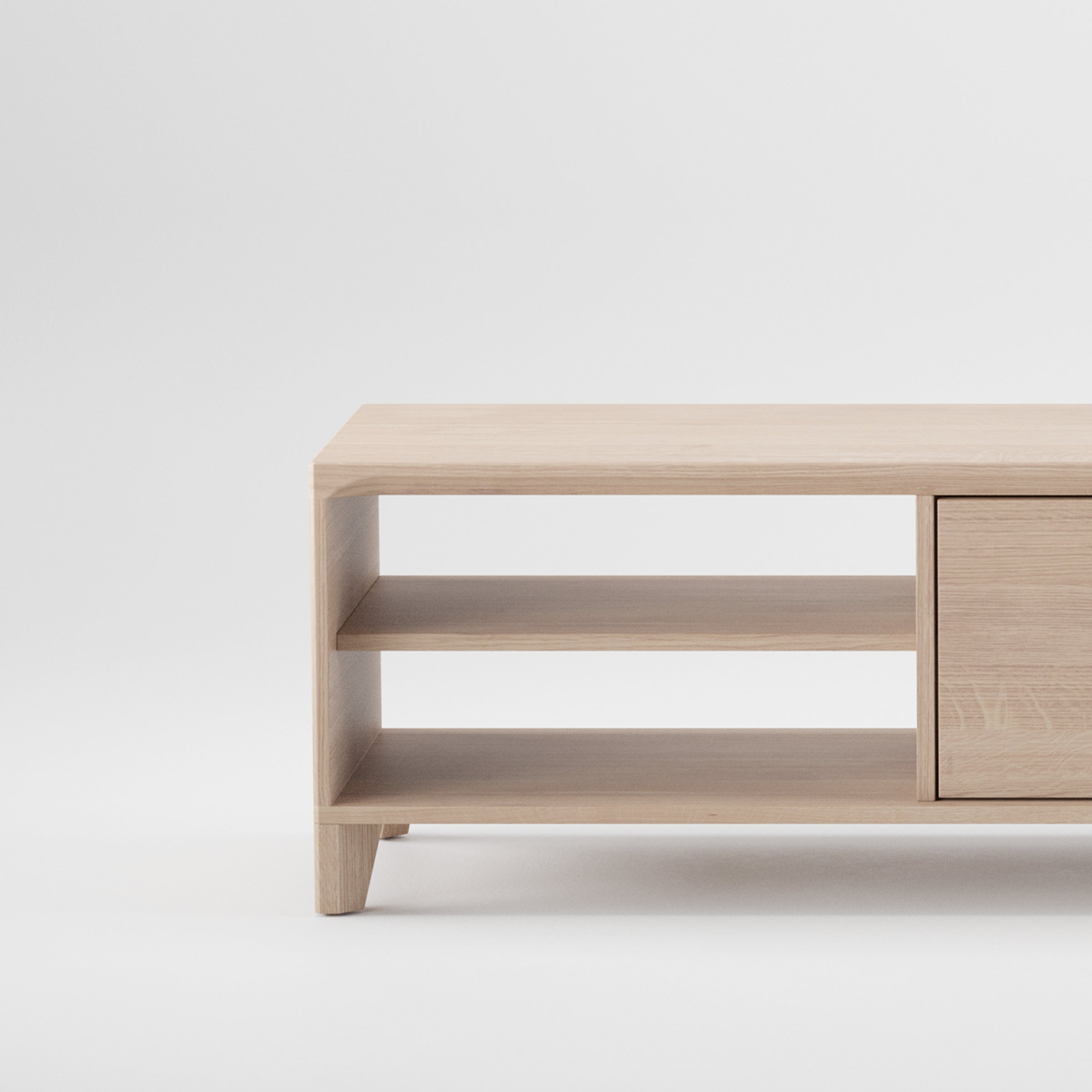 The HANNY Lowboard by Artisan is a minimalist wooden cabinet with solid wood construction, featuring two open shelves on the left and a closed compartment on the right. Its simple, elegant design highlights a natural wood texture with an eco-friendly finish against a plain white background.