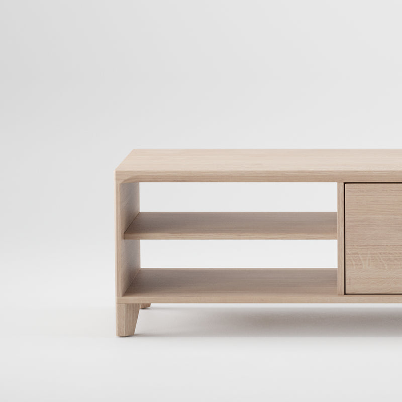 The HANNY Lowboard by Artisan is a minimalist wooden cabinet with solid wood construction, featuring two open shelves on the left and a closed compartment on the right. Its simple, elegant design highlights a natural wood texture with an eco-friendly finish against a plain white background.