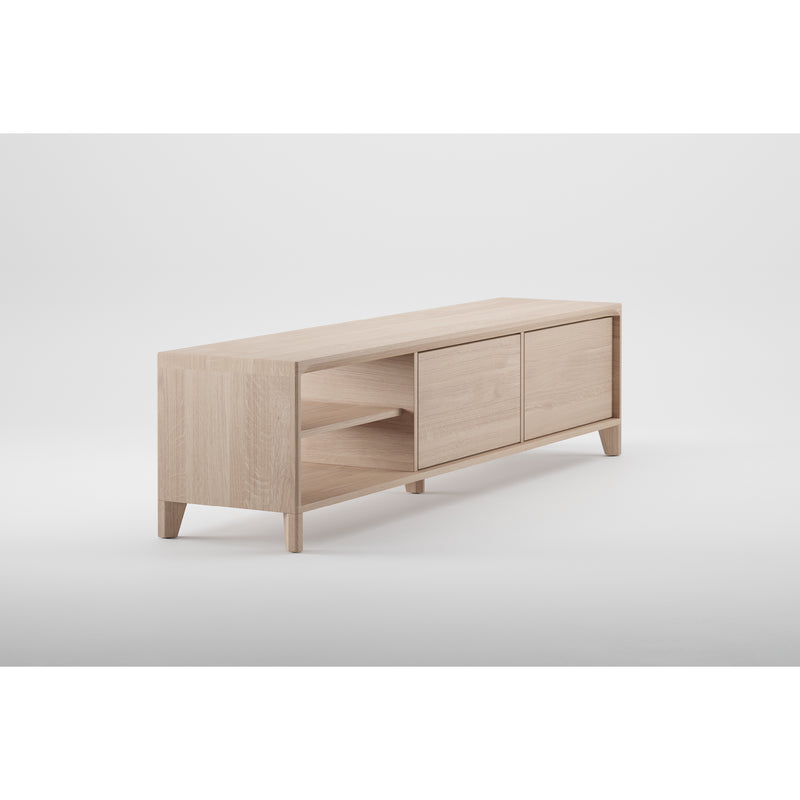 The Artisan HANNY Lowboard showcases a light natural finish that highlights the wood texture. It features two open shelves on the left, two closed cabinets on the right, and offers solid wood construction with a simple modern design, clean lines, and short legs.