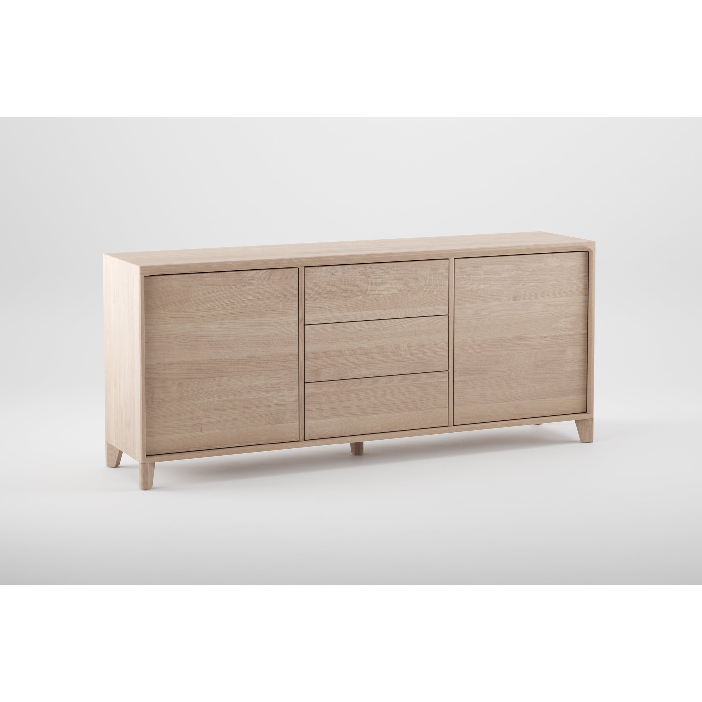 The HANNY Sideboard by Artisan is crafted from solid wood, showcasing a minimalist design. It features two doors on each side, three central drawers, tapered legs, and a smooth natural finish with eco-friendly oils and wax against a white background.
