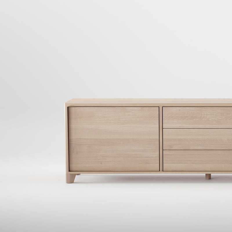 The HANNY Sideboard by Artisan is a minimalist light wood cabinet on a plain white background. Its crafted from solid wood, finished with natural oils and wax, featuring a left door and two right horizontal drawers for simple, modern storage.