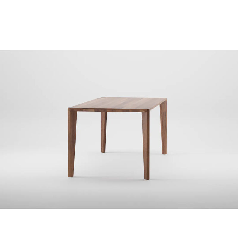 The Artisan HANNY Table presents a minimalist design with a solid wood rectangular top and four tapered legs, finished in natural oils and wax, styled against a plain white backdrop.