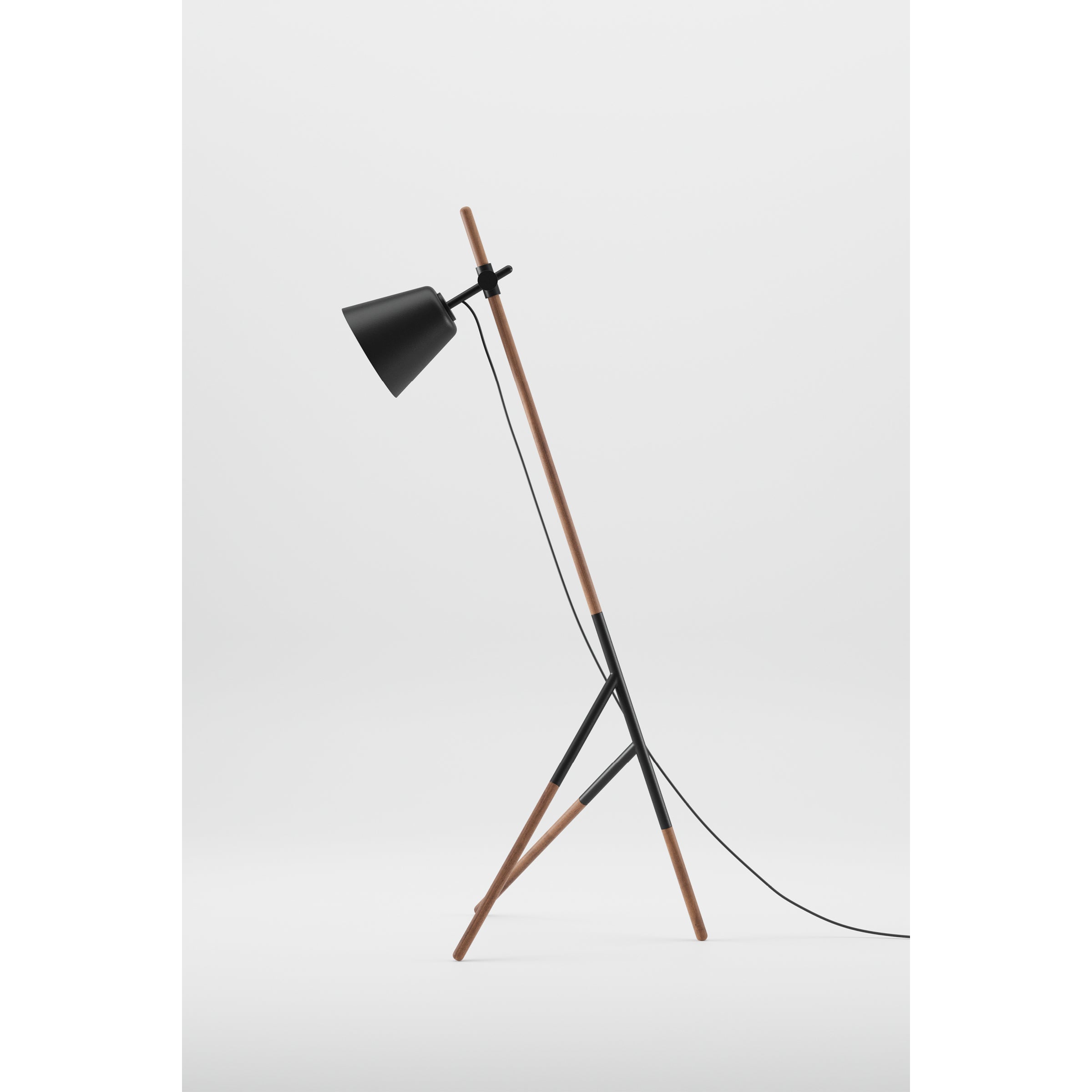 The Artisan INSERT Floor Lamp showcases a modern design with a solid wood tripod base, black metal shade, slim angled structure, and visible power cord. Its crafted from eco-friendly materials and displayed against a plain white background.