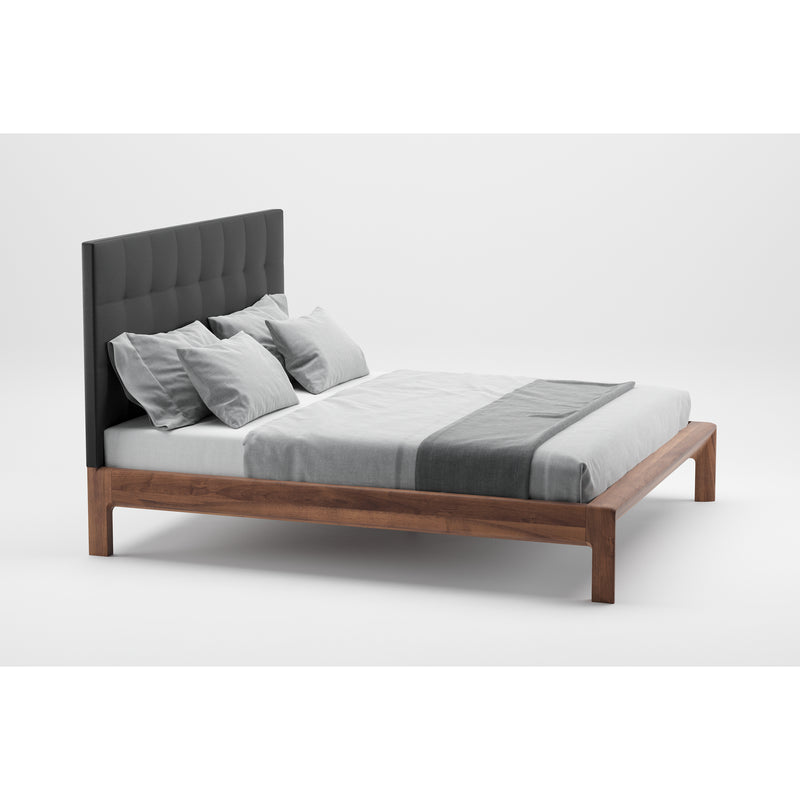 The INVITO Bed by Artisan showcases a modern design with artisan wood furniture. Its wooden frame and black tufted headboard complement neatly arranged pillows, a white sheet, and a gray blanket. The natural wood texture stands out against the plain white background, enhancing its minimalist appeal.