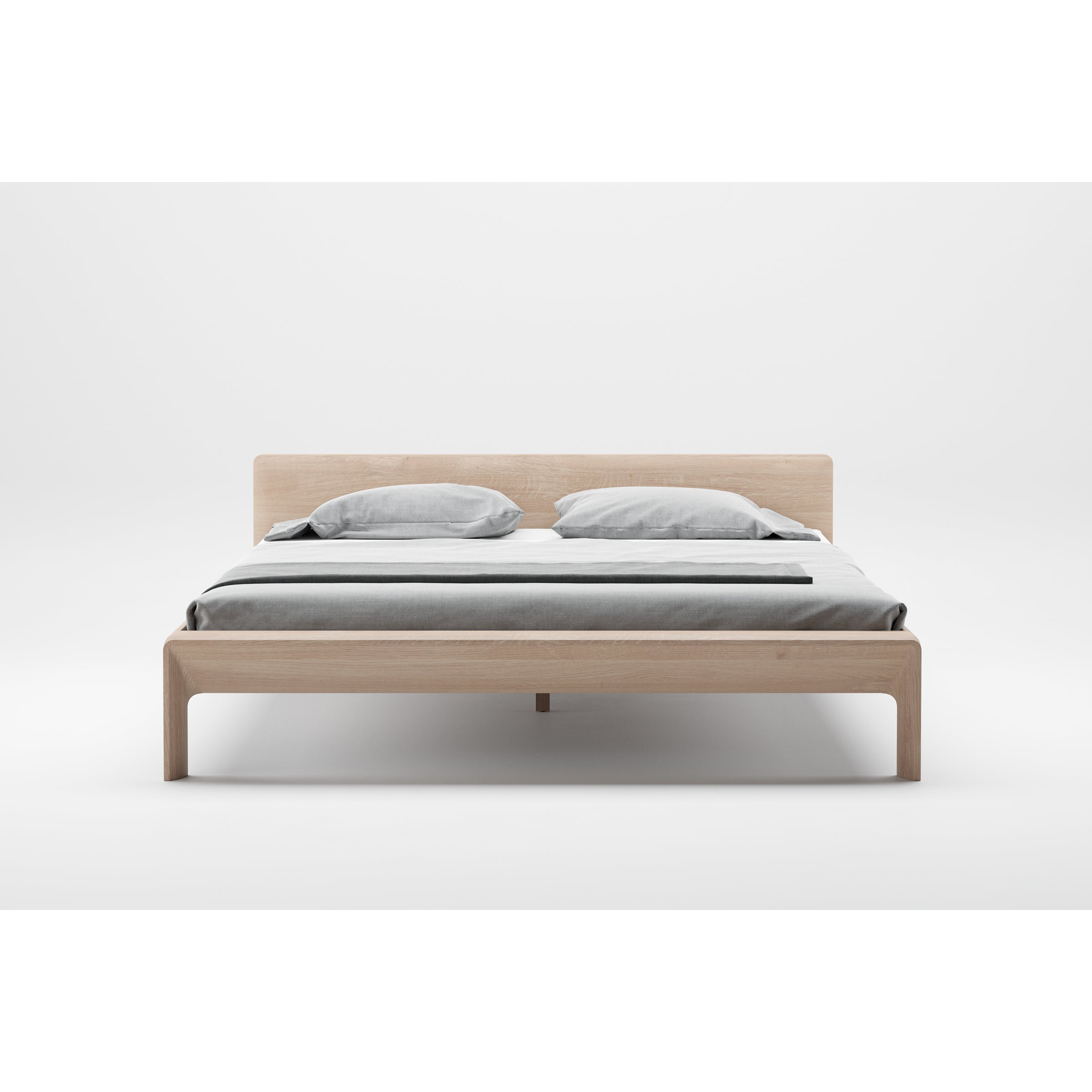 The INVITO Bed by Artisan features a minimalist design with a light wood frame and simple headboard, highlighting its natural wood texture. Its elegantly dressed in gray bedding with two pillows and a matching duvet, while the surrounding white space accentuates its artisan craftsmanship.