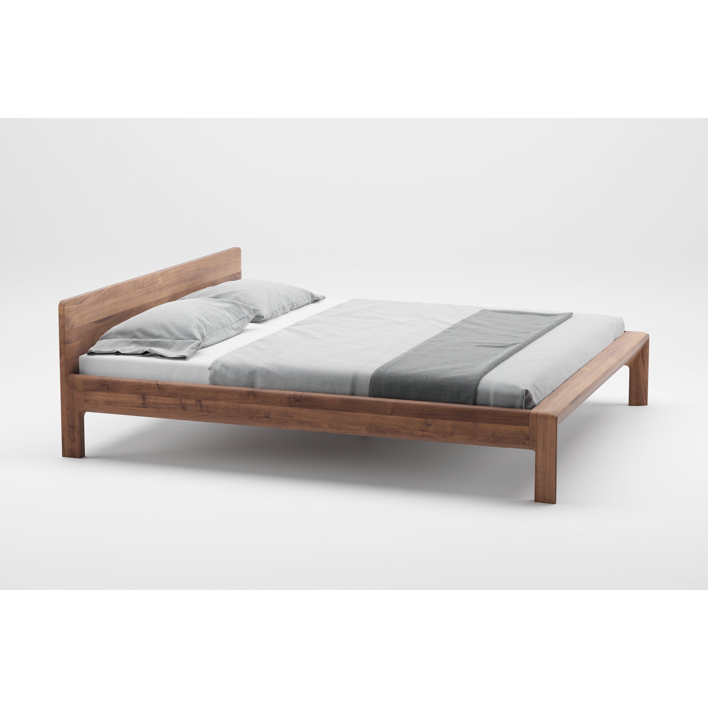 The Artisan INVITO Bed is a minimalistic wooden bed frame with a natural wood texture and simple headboard. It includes a grey and white bedspread with two matching pillows, crafted from eco-friendly materials, and set against a plain white background.