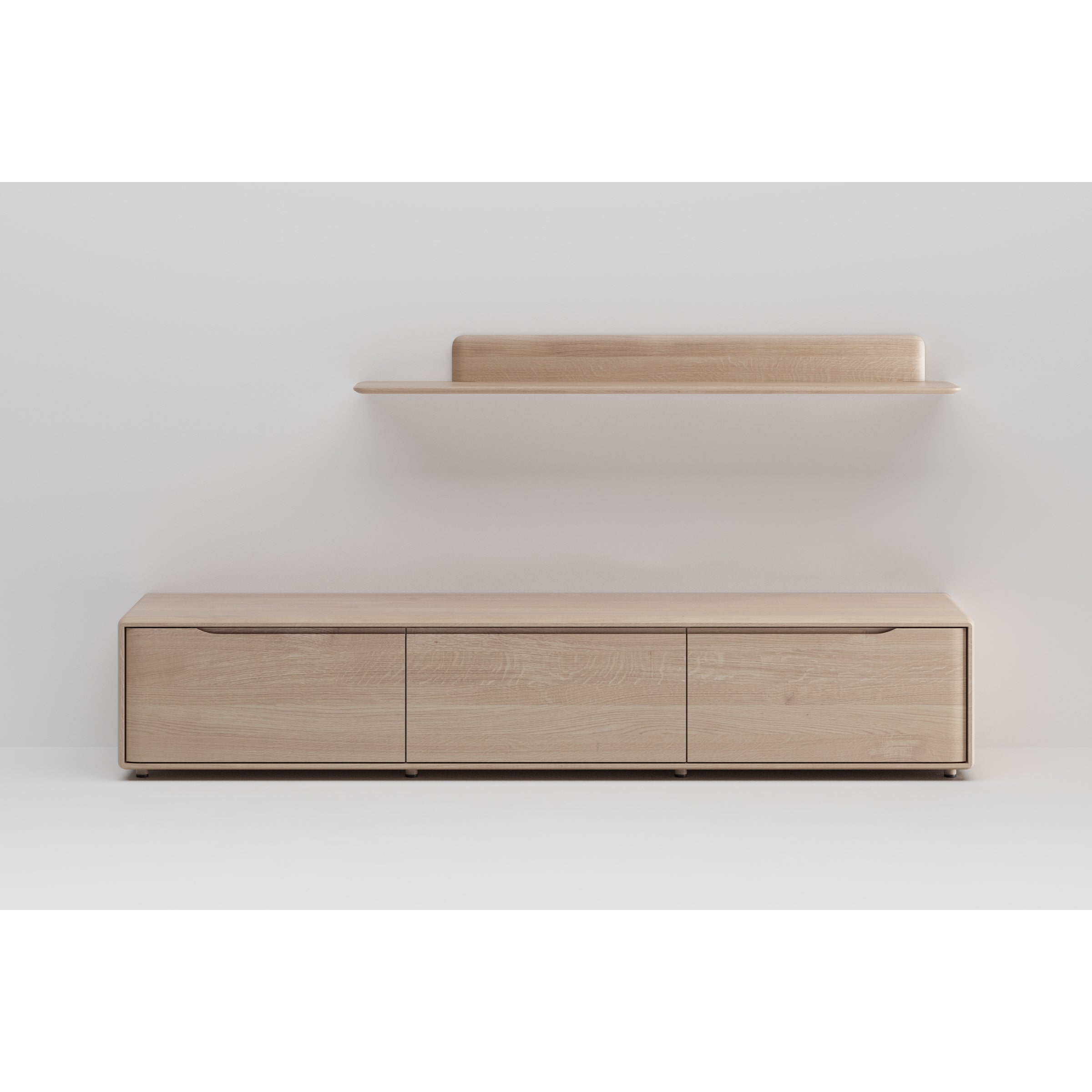 The INVITO MS Lowboard by Artisan is a minimalist wooden TV stand with three drawers, crafted from solid wood and set against a white wall. Above it is a matching floating shelf with a rounded back, completing the artisan furniture look for a simple and modern style.