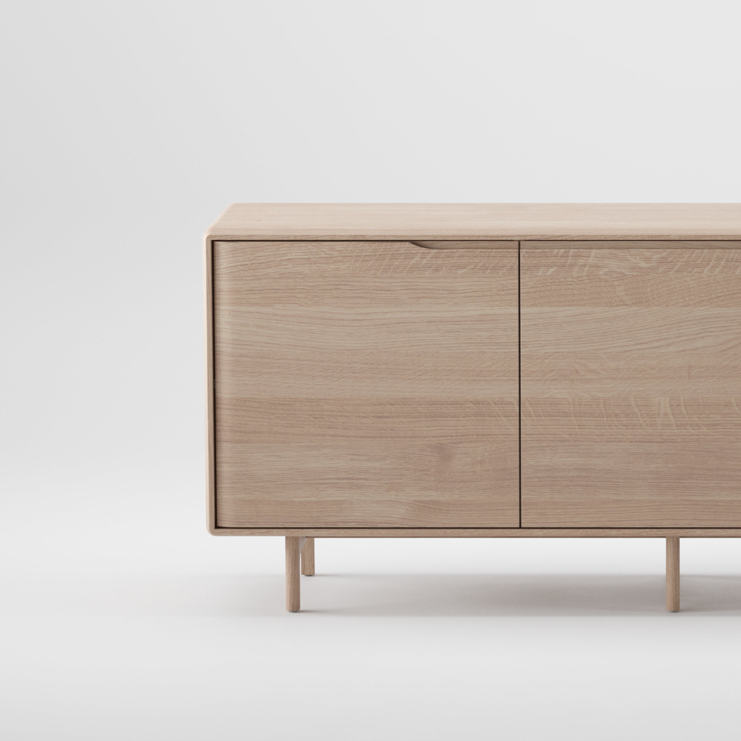 The Artisan INVITO Sideboard is a minimalist wooden cabinet made from solid wood with a natural finish. It has two doors, sleek straight legs, and an eco-friendly modern design against a plain white background.