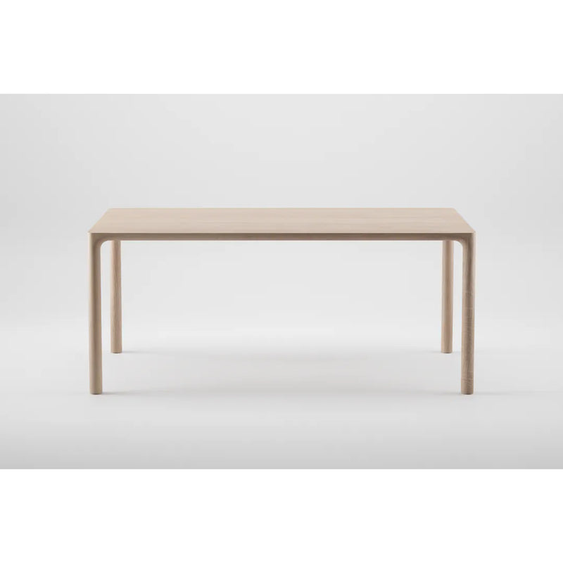 The JEAN Table by Artisan is a minimalist piece featuring a solid wood construction with a rectangular top and sleek, simple legs, showcasing exquisite craftsmanship against a light gray background.