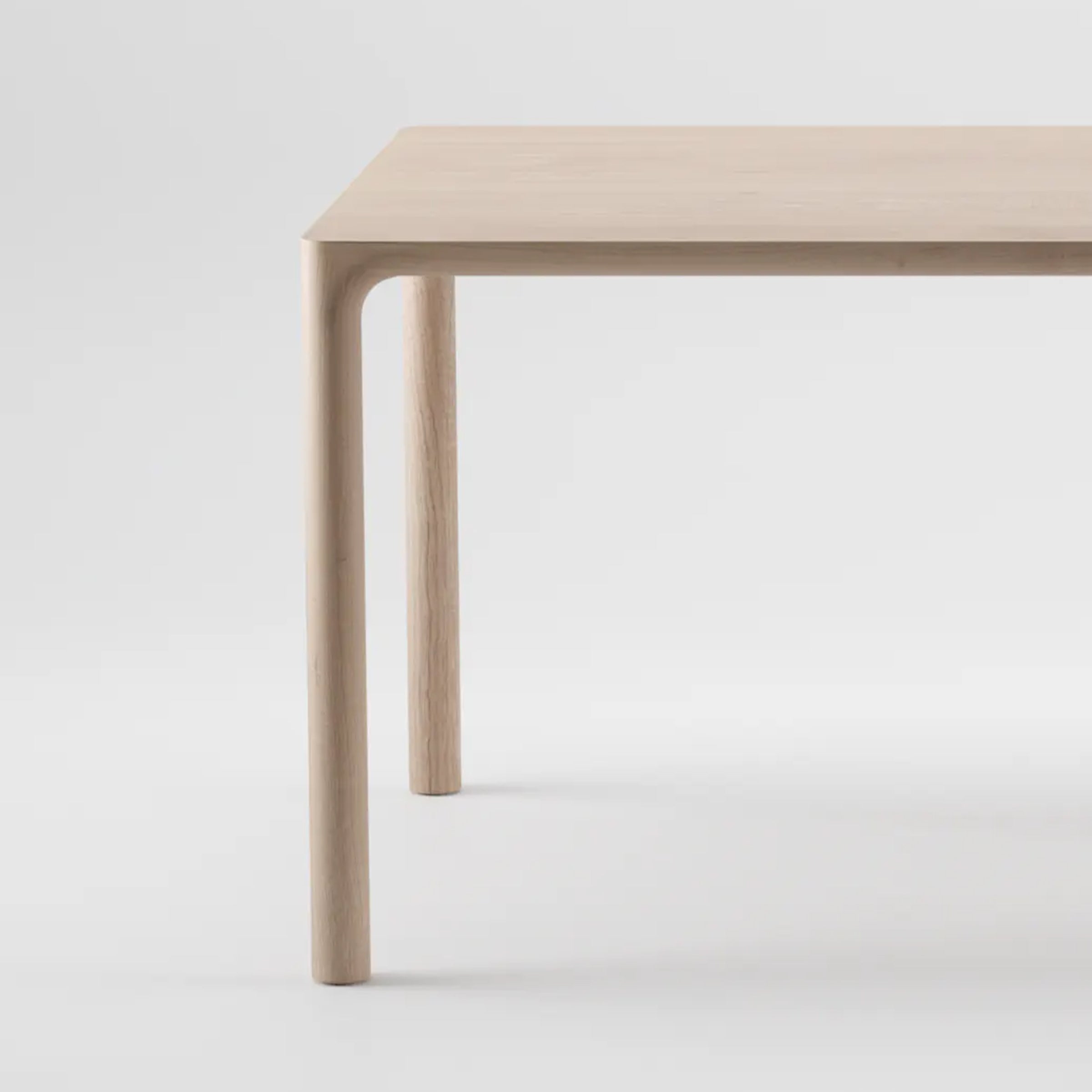 The JEAN Table by Artisan features a minimalist design with a solid wood composition and light beige finish. Its flat, rectangular surface and four sturdy legs, showcased on a plain light gray background, highlight its fine craftsmanship and simple elegance.