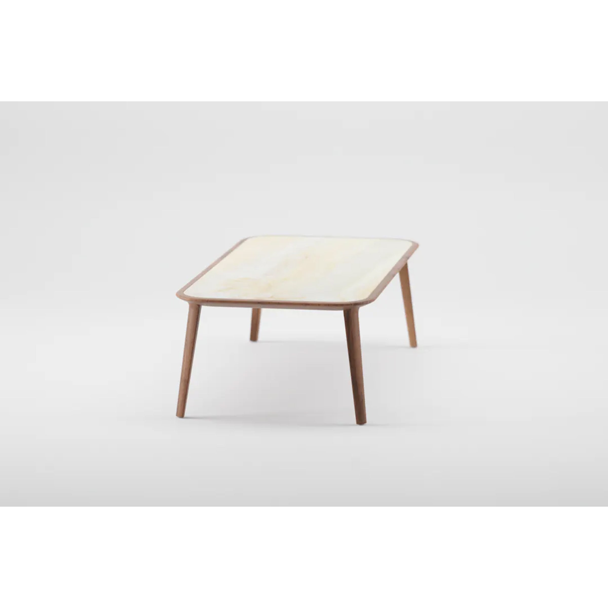 The KALOTA Coffee Table by Artisan is a minimalist piece crafted from solid wood, featuring a light-colored top and angled wooden legs finished with natural oils, set against a plain white background.