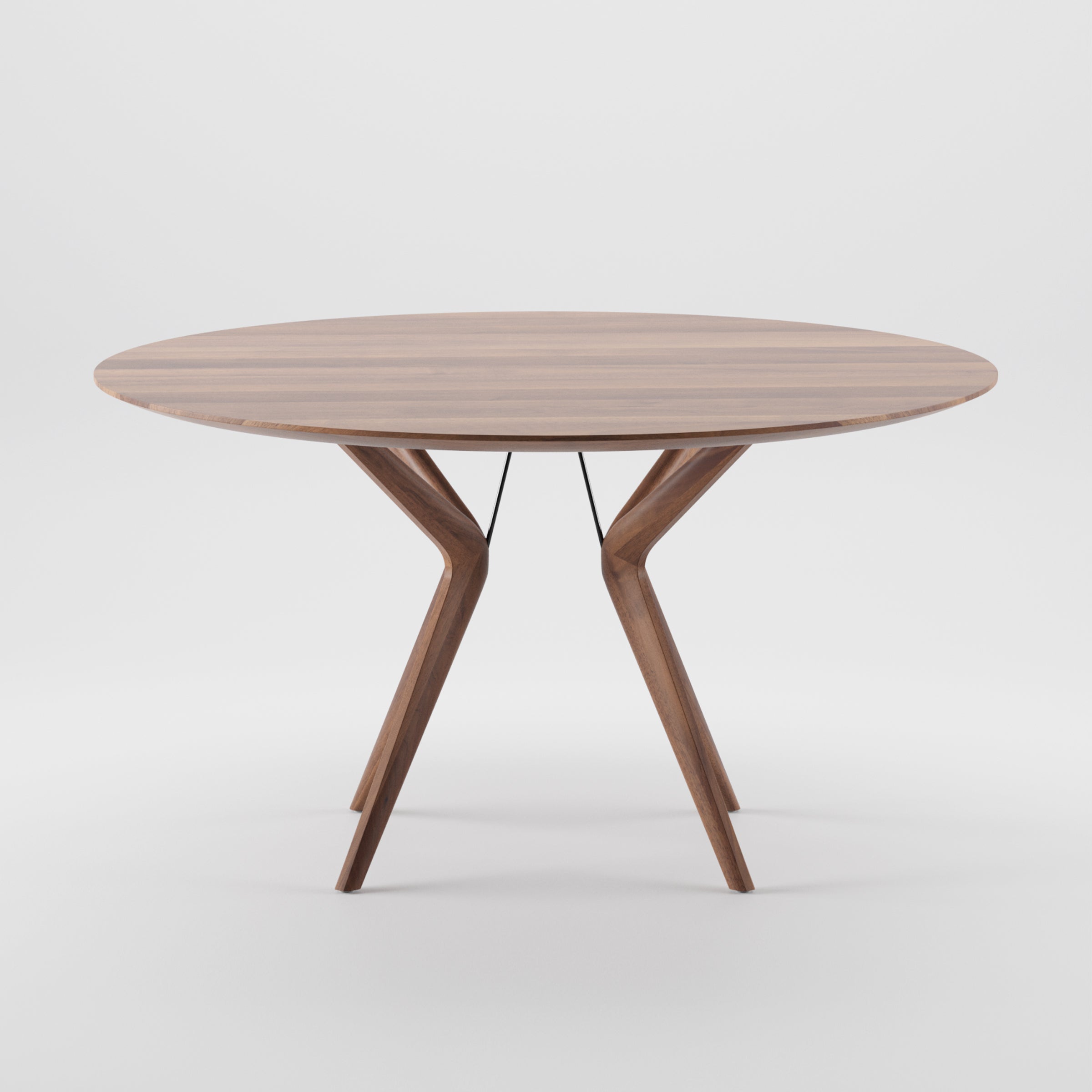 The Artisan LAKRI Round Table features a modern design with angled legs, crafted from solid wood with a smooth surface. Coated in natural oils, it stands against a white background, showcasing its contemporary style and eco-friendly materials.