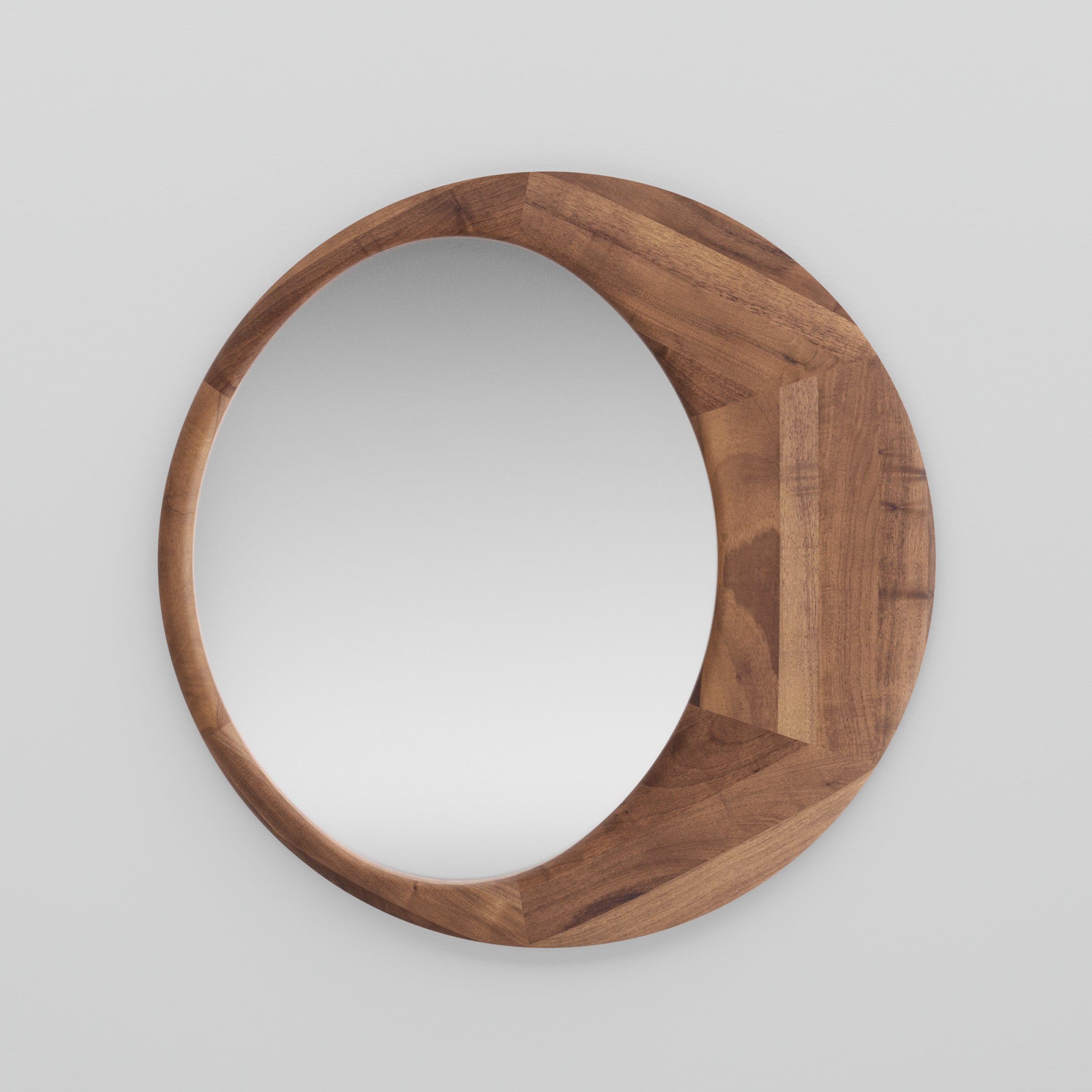 The Artisan Lana Mirror features a round design with a solid wood frame against a plain white background. Treated with natural oils, the frame showcases a beautiful wood grain pattern, enhancing the minimalist design with texture and warmth.