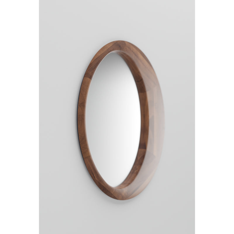 The Lana Mirror by Artisan features a round design with a thick solid wood frame finished with natural oils, beautifully showcasing the wood grain on a plain, light-colored wall. It subtly reflects its surroundings and embodies eco-friendly materials.