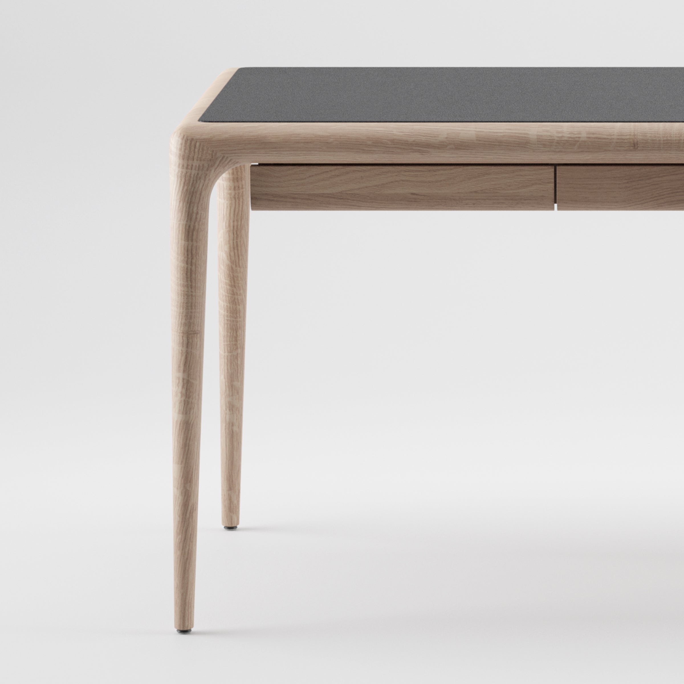 The LATUS Leather Desk by Artisan features a sleek, minimalist design with curved legs and a modern dark tabletop crafted from eco-friendly materials, beautifully contrasting against a white background.