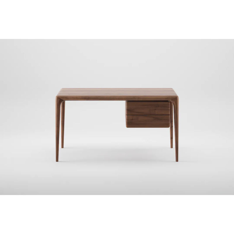 The Artisan LATUS Desk boasts a minimalist, modern aesthetic with a sleek solid wood design. Featuring narrow legs and two layered drawers on the right, its organic beauty is highlighted by a plain white backdrop.