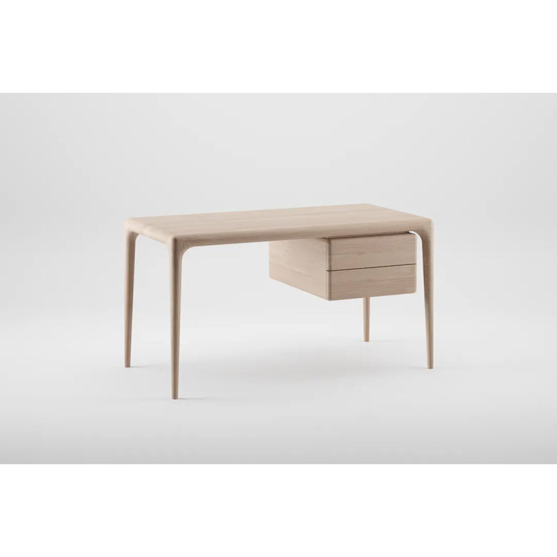 The LATUS Desk by Artisan is a minimalist piece featuring sleek, tapered legs and two right-side drawers. Crafted from solid wood, it boasts a light, natural finish set against a plain white background, highlighting its organic beauty.