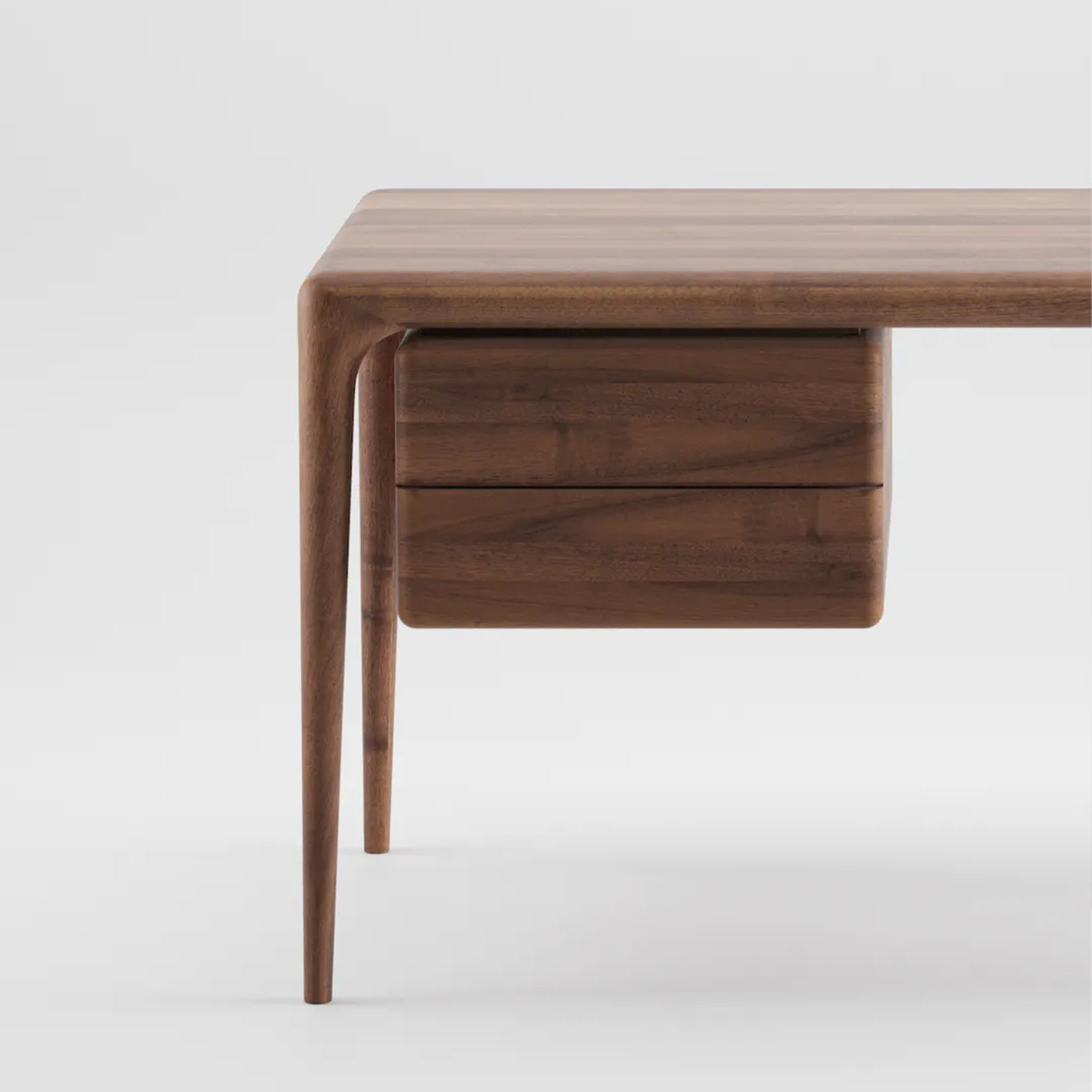 The Artisan LATUS Desk is crafted from solid wood with a polished finish. It has a minimalist design, featuring a single right-side drawer and slightly tapered legs that highlight its organic beauty, set against a plain white background.