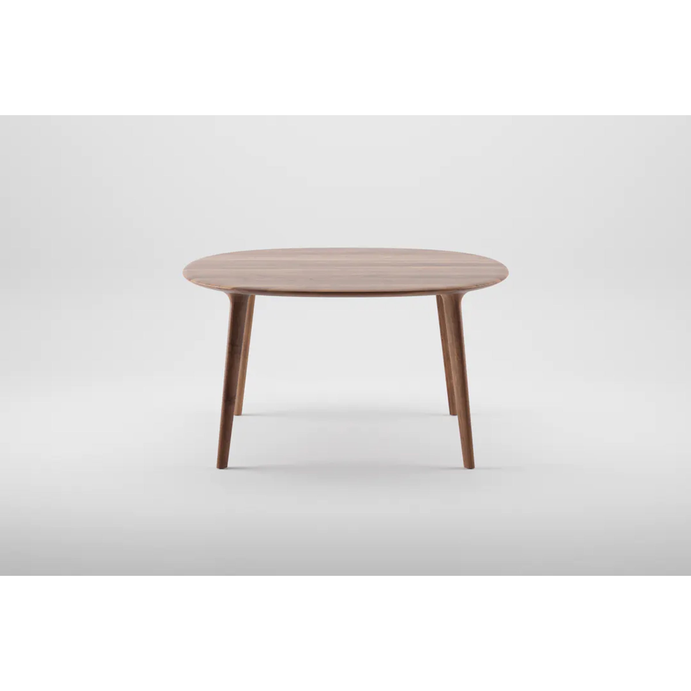 Against a gray background, the LUC Table Round by Artisan highlights its minimalist modern design with a smooth surface and four tapered legs. The tactile design showcases exquisite wood finishes, blending craftsmanship with contemporary elegance.