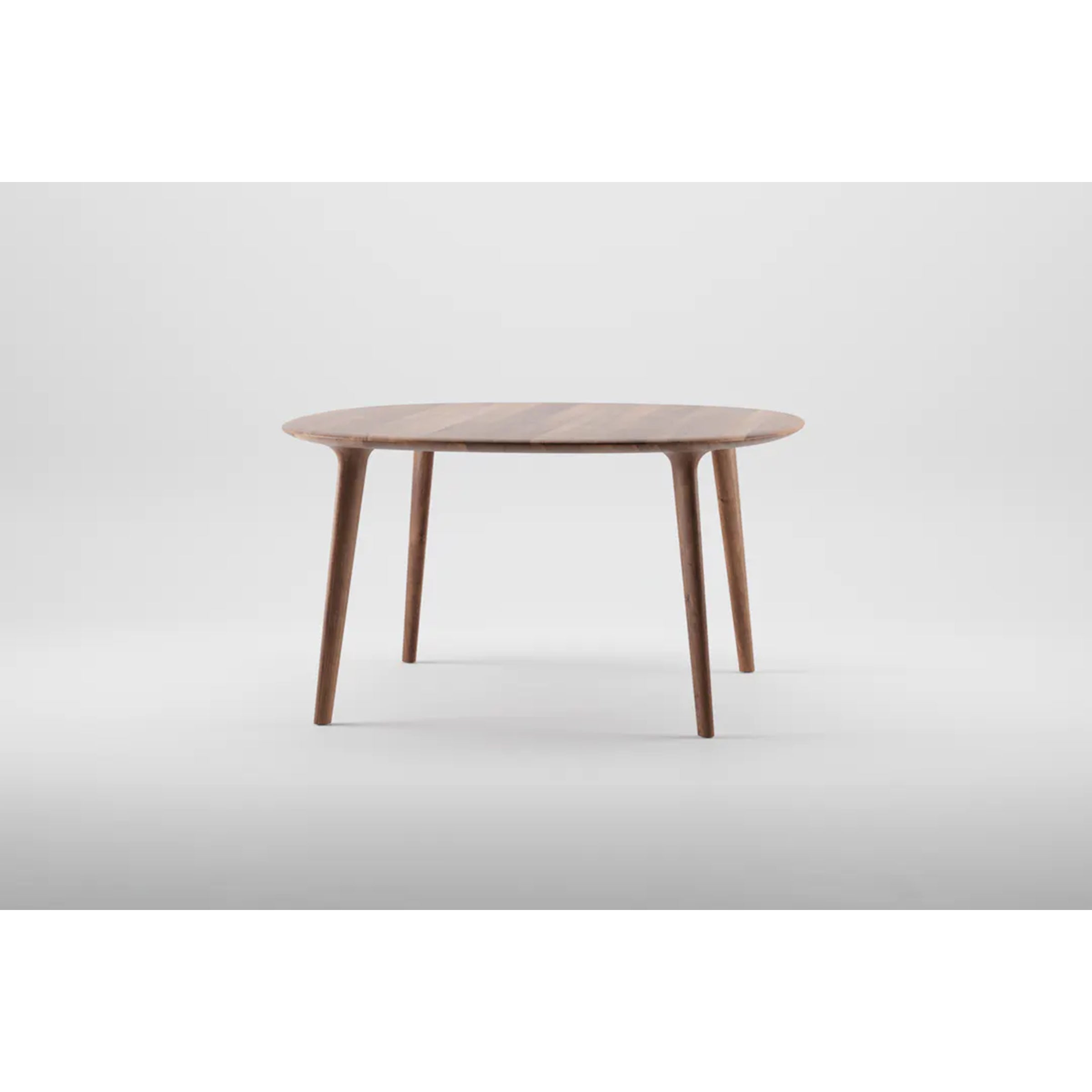The LUC Table Round by Artisan epitomizes artisanal wood furniture, featuring four slender, tapered legs and a sleek minimalist design. With its smooth light brown finish, this tactile wooden table embodies understated elegance against a plain white background.
