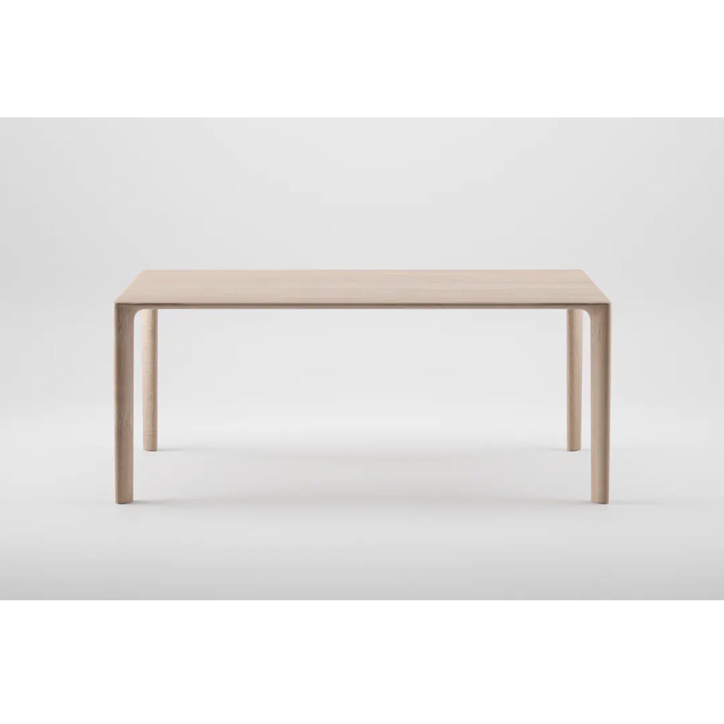 The MELA Table by Artisan is a minimalist piece crafted from solid wood with a light finish. It features a simple rectangular design, four straight legs, and is treated with natural oils to highlight its clean lines and eco-friendly modern aesthetic against a plain white background.