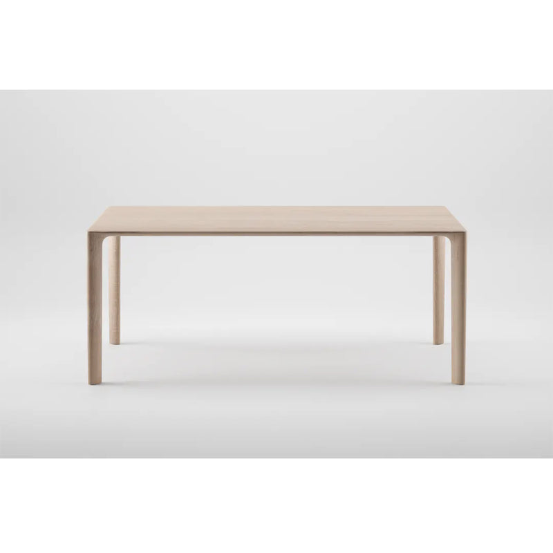 The MELA Table by Artisan is a minimalist piece crafted from solid wood with a light finish. It features a simple rectangular design, four straight legs, and is treated with natural oils to highlight its clean lines and eco-friendly modern aesthetic against a plain white background.