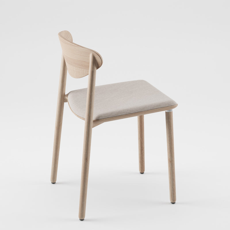 The NARU Chair Light by Artisan, crafted from solid wood and finished with natural oils, features a light curved backrest and a cushioned beige seat. It is positioned at an angle on a plain white background.