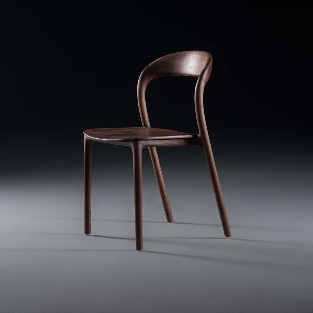 The NEVA light chair by Artisan from the Neva collection features a sleek, modern design with a curved backrest and slender legs, showcased against a dark gradient background. It highlights smooth lines and exquisite wood craftsmanship.