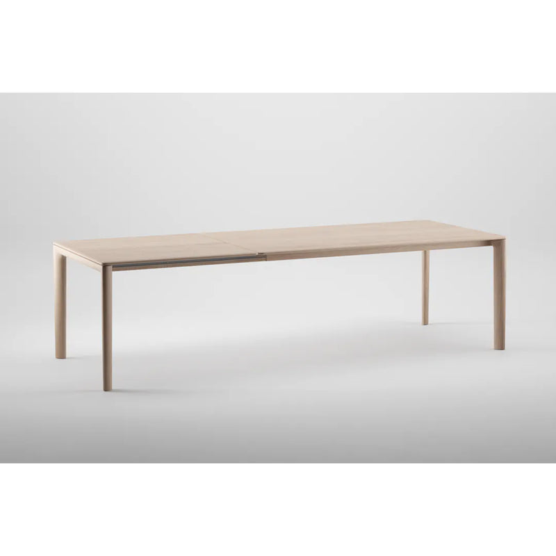 The NEVA Table Extendable by Artisan, made from natural wood, showcases a minimalist design with clean lines and slender legs against a plain gray background.