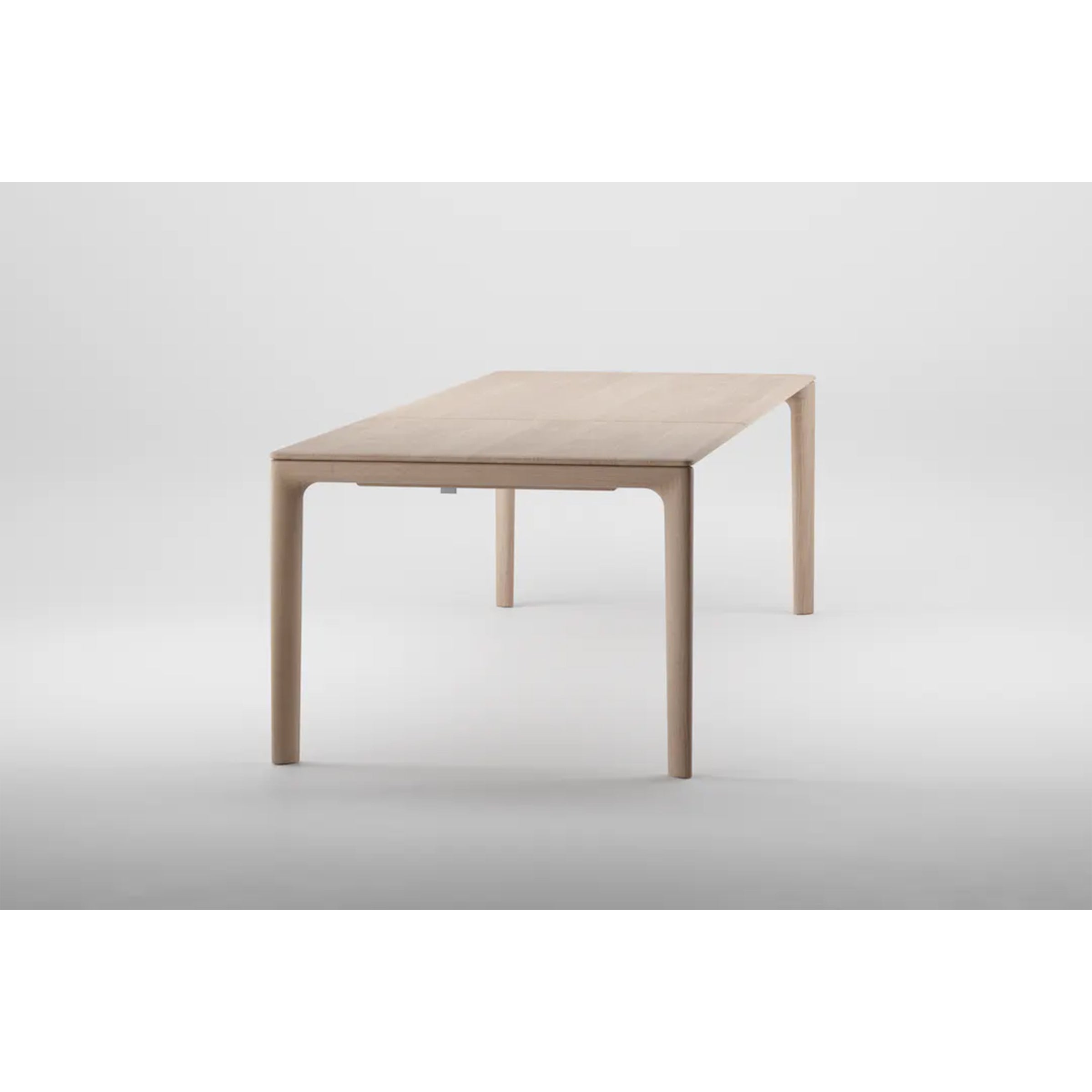 The NEVA Table Extendable by Artisan is a minimalist wooden dining piece. Its clean lines and slightly rounded edges, set against a plain white background, highlight its artisanal craftsmanship and modern design with a light, natural finish.
