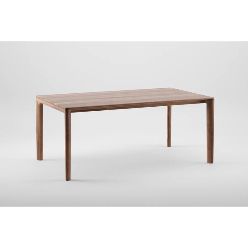 The NEVA Table by Artisan is a wooden rectangular table with a simple modern design, featuring a smooth flat surface and four straight legs. Its artisanal craftsmanship and natural finish stand out against a plain light gray background.