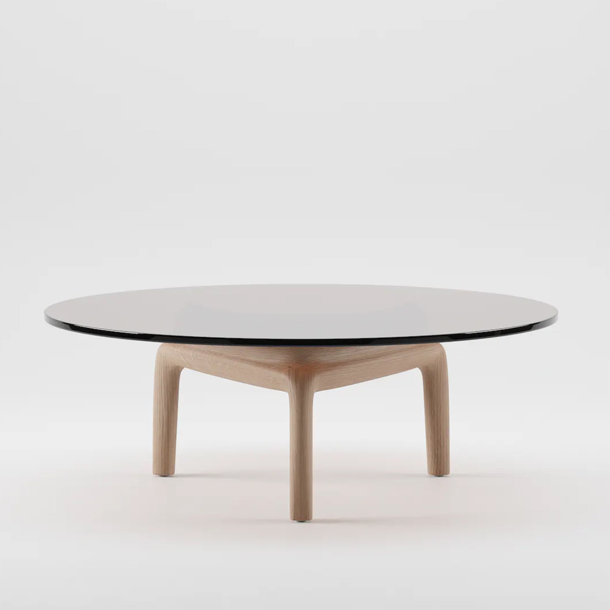 The PASCAL Coffee Table by Artisan features a minimalist design with a round black glass top and a light wooden base made from eco-friendly solid wood. Its three-legged structure creates a striking contrast against any white background.