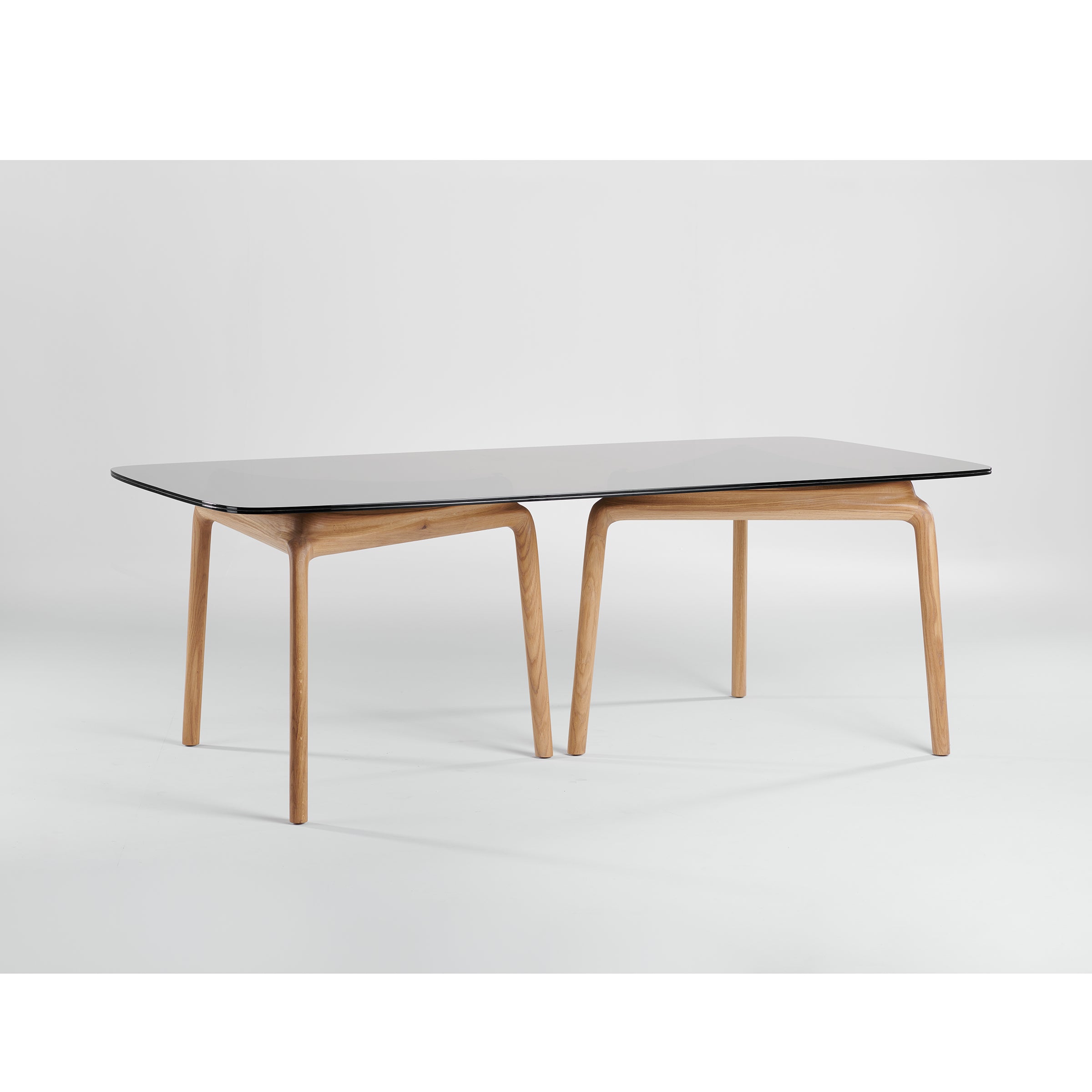 The PASCAL Rectangular Table by Artisan features a minimalist design with a black top and angled legs. Crafted from solid wood, it showcases a natural texture against a plain white background, emphasizing environmentally-friendly materials for sustainable style.