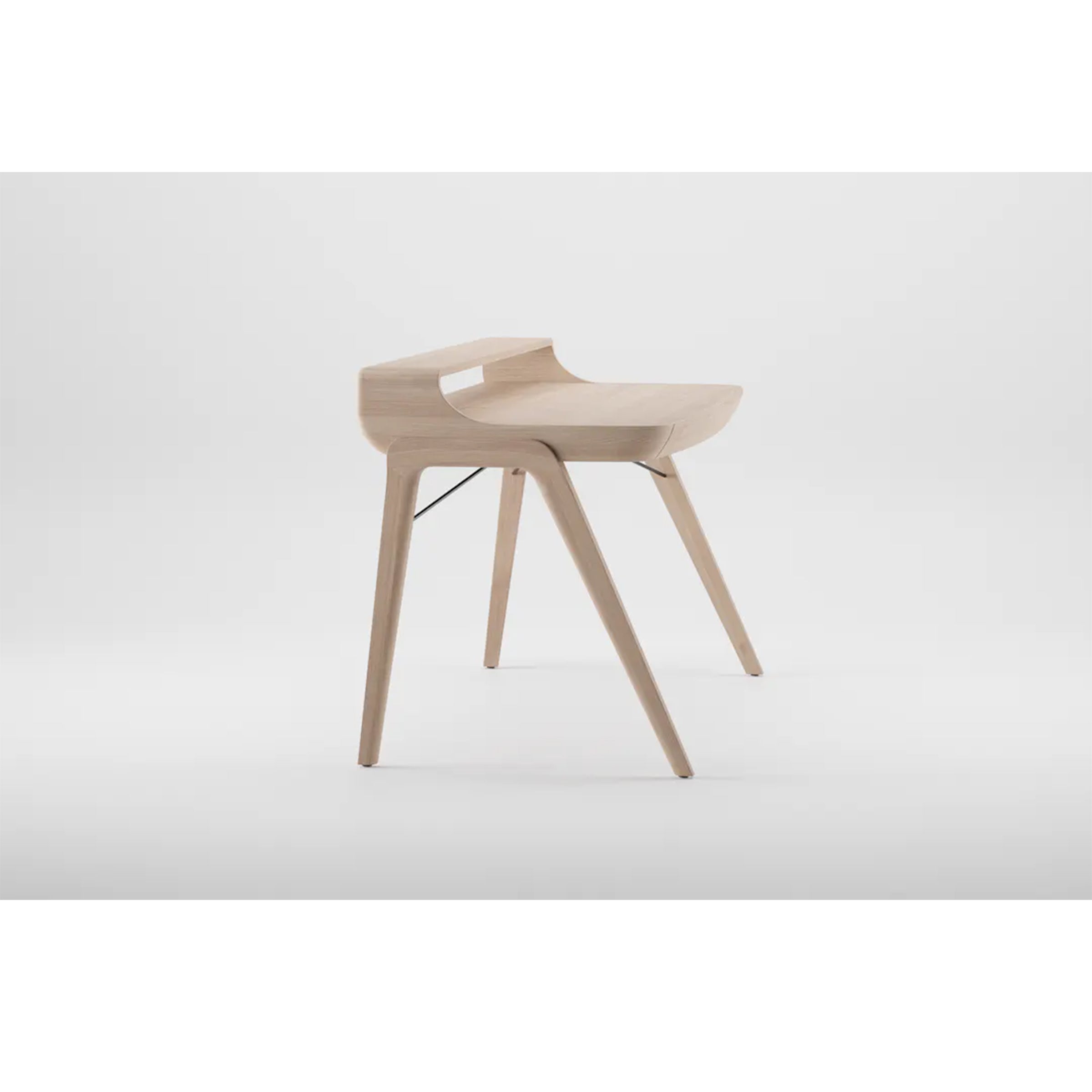 The Artisan PICARD Desk is a minimalist piece crafted from solid wood, showcasing sleek curved lines and a light natural finish. Its four angled legs and low backrest integrate seamlessly into the design, offering modern elegance against a plain white background.