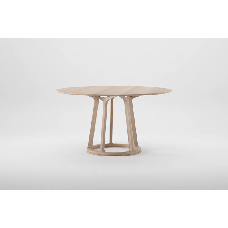 The PIVOT Round Table by Artisan is a round wooden table made from solid wood with a light finish. It has four angled supports on a circular base and is treated with natural oils for an eco-friendly design, standing out against the plain white background.