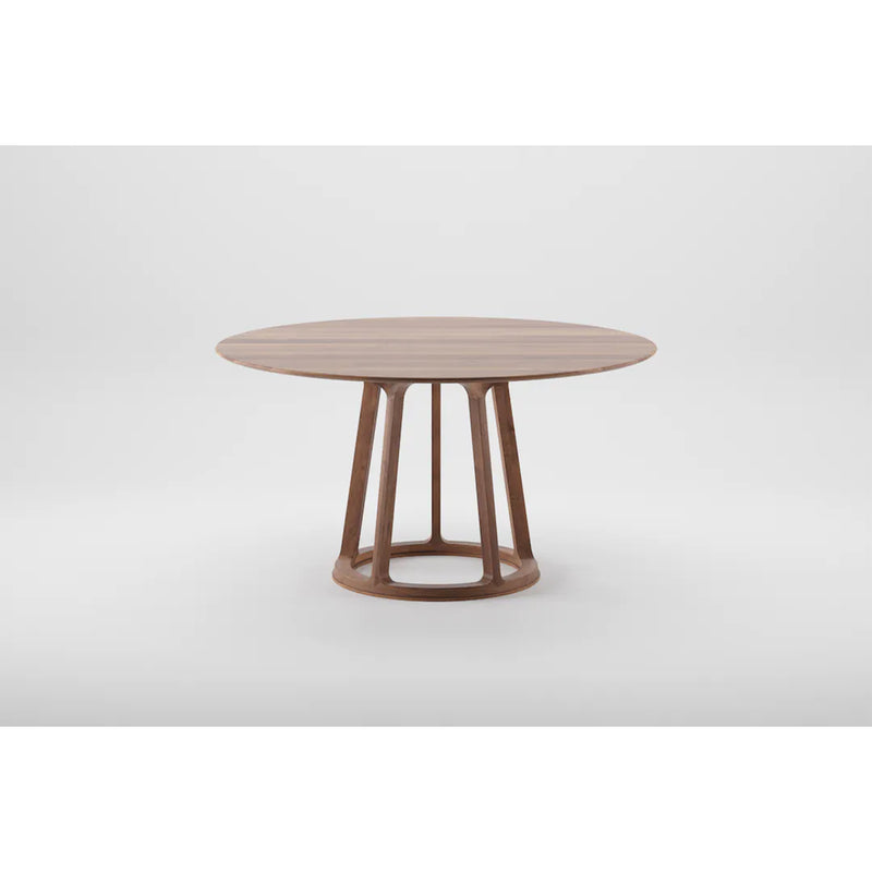 The PIVOT Round Table by Artisan features a solid wood top and geometric base with four angled legs connected by a circular support, crafted from eco-friendly materials and natural oils, set against a plain light gray background.