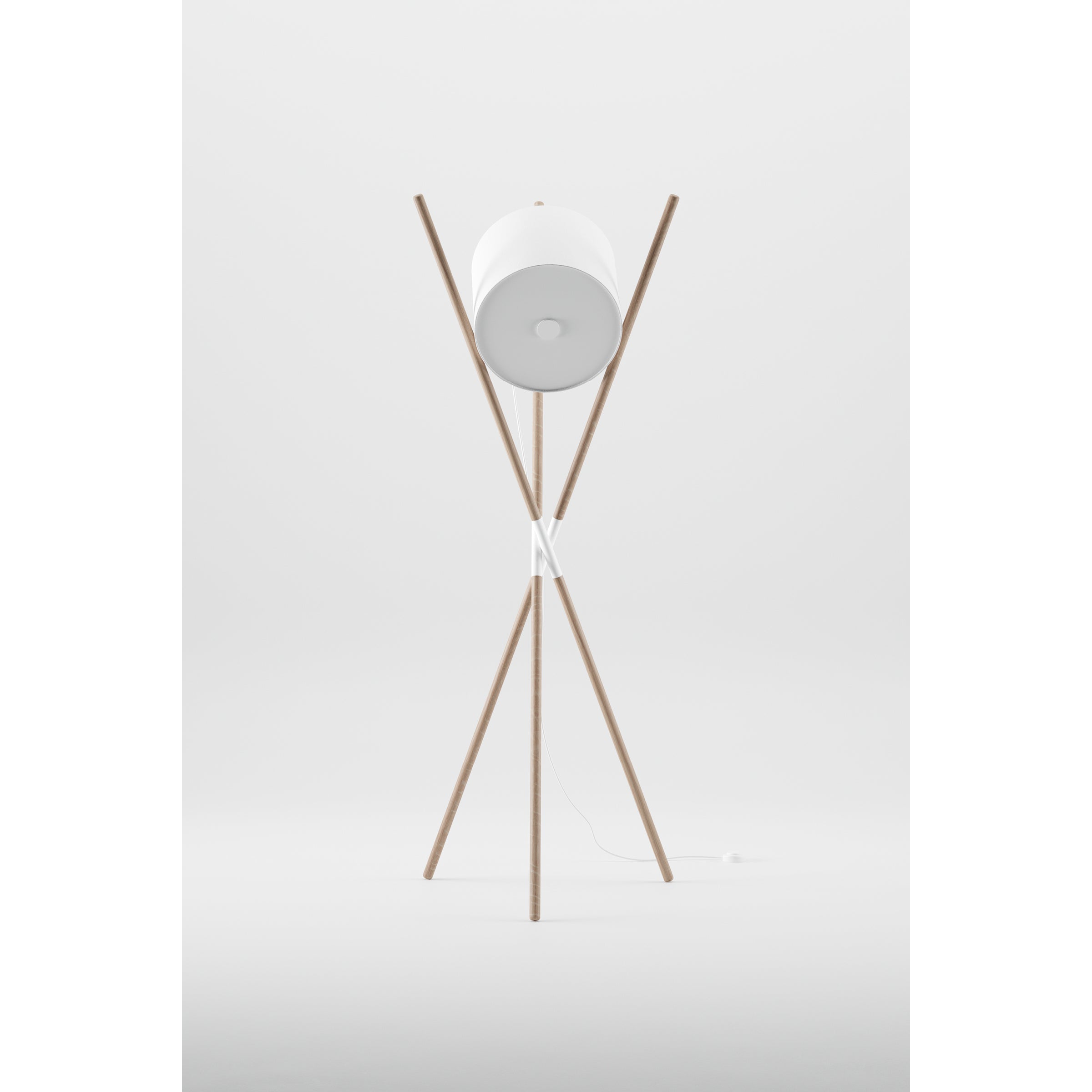 The SHIFT Lamp by Artisan is a modern floor lamp with a flat-pack design featuring a tripod base made of wooden struts, a cylindrical white lampshade, and intersecting poles for balance. A white cord elegantly rests at the base, complementing its minimalist style.