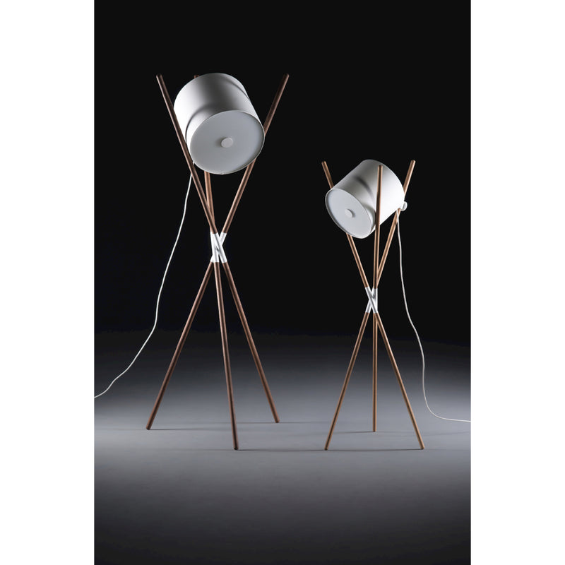 Two Artisan SHIFT Lamps feature white cylindrical shades on wooden tripod stands with sleek struts at varying heights. The lamps have a flat-pack design and are set against a dark background with visible white power cords.