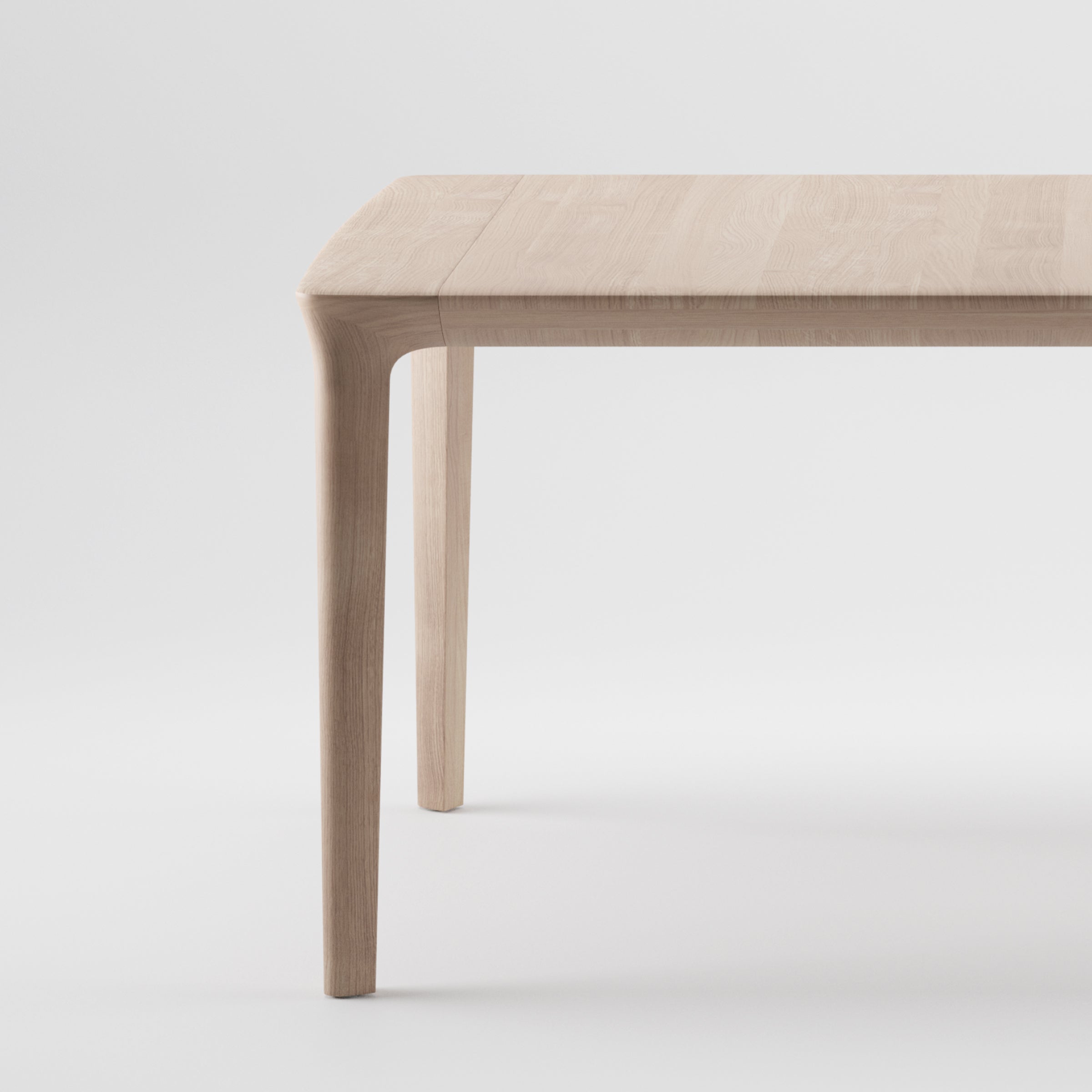 The TARA Extendable Table by Artisan features a minimalist design with smooth, rounded edges and four slender legs. Its light, natural wood finish enhances its organic beauty against a plain white background.