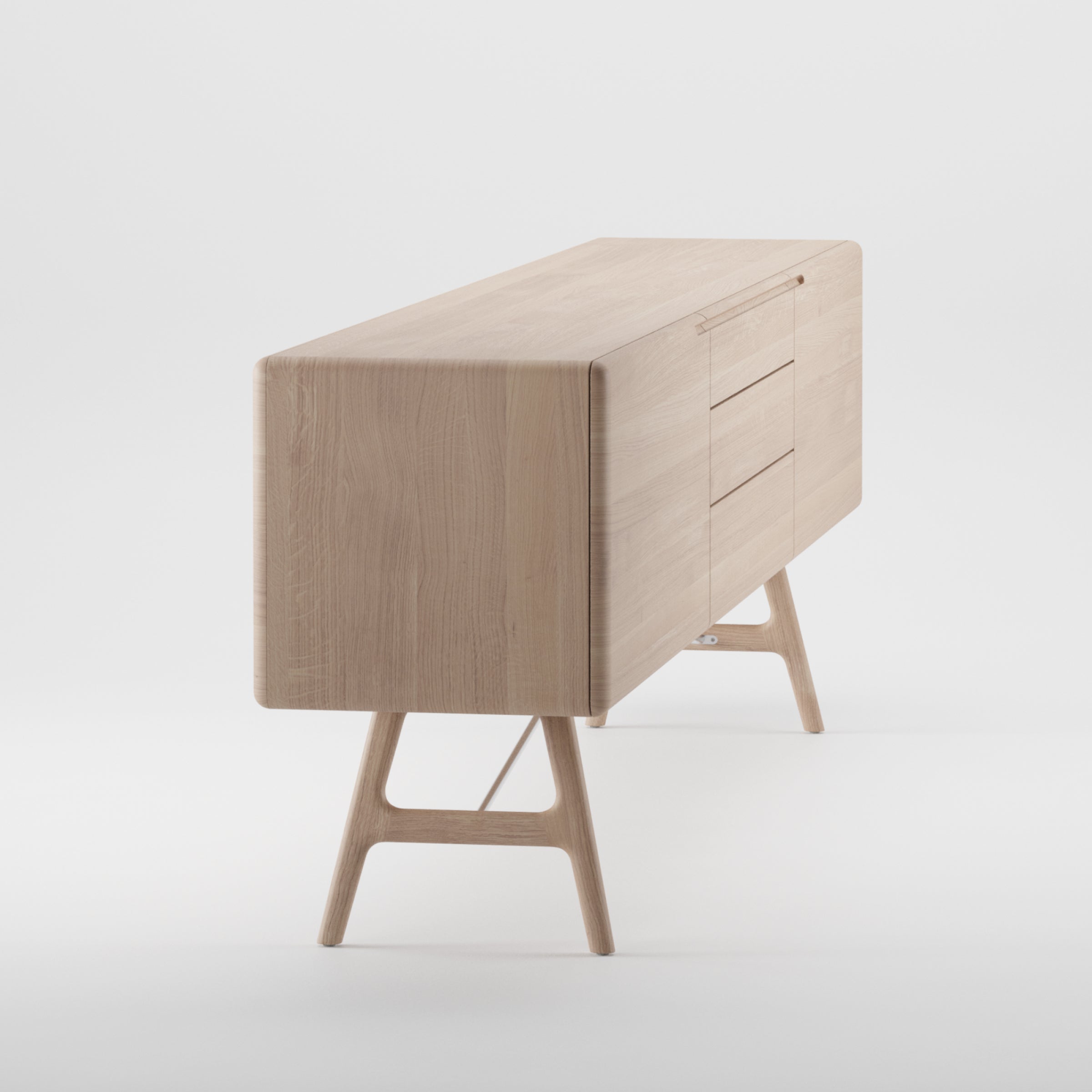 The Artisan TESA Sideboard is a minimalist piece crafted from solid wood featuring a smooth finish, enhanced with natural oils. It includes three right-side drawers and two left-side doors on angled legs, set against a white background.