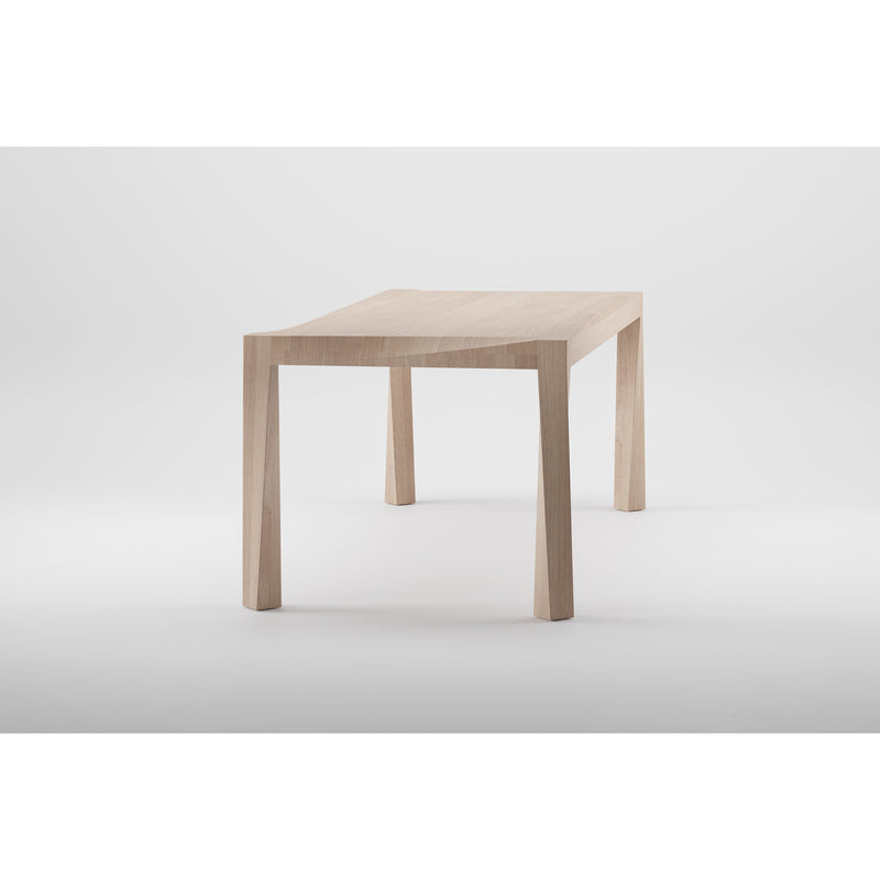 The TORSIO Table by Artisan is a minimalist piece crafted from solid wood with a light, natural finish. It features a simple design with four straight legs and a rectangular top, enhanced by eco-friendly materials and natural oils against a plain white background.