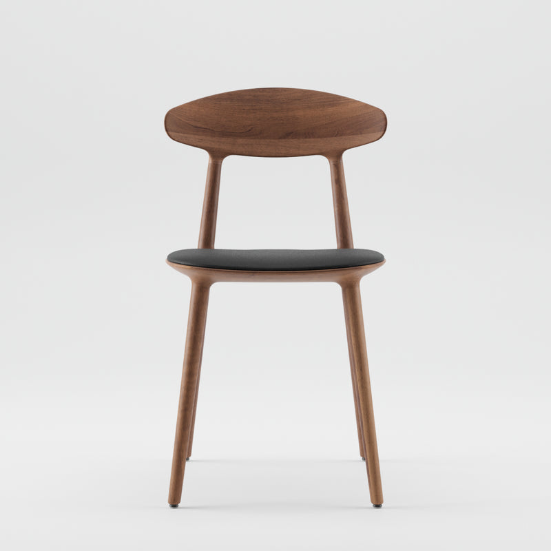 The WU Chair by Artisan is a modern wooden chair made from solid wood and natural oils. It features a curved backrest, black cushioned seat, and smooth, rounded legs in a sleek, minimalist design against a plain white background.