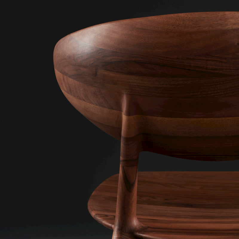 Close-up of the Artisan WU Chair, crafted from solid wood with a smooth, dark brown grain. The image showcases its elegant curved backrest and round slender leg, enhanced with natural oils for a modern polished finish against a dark background.