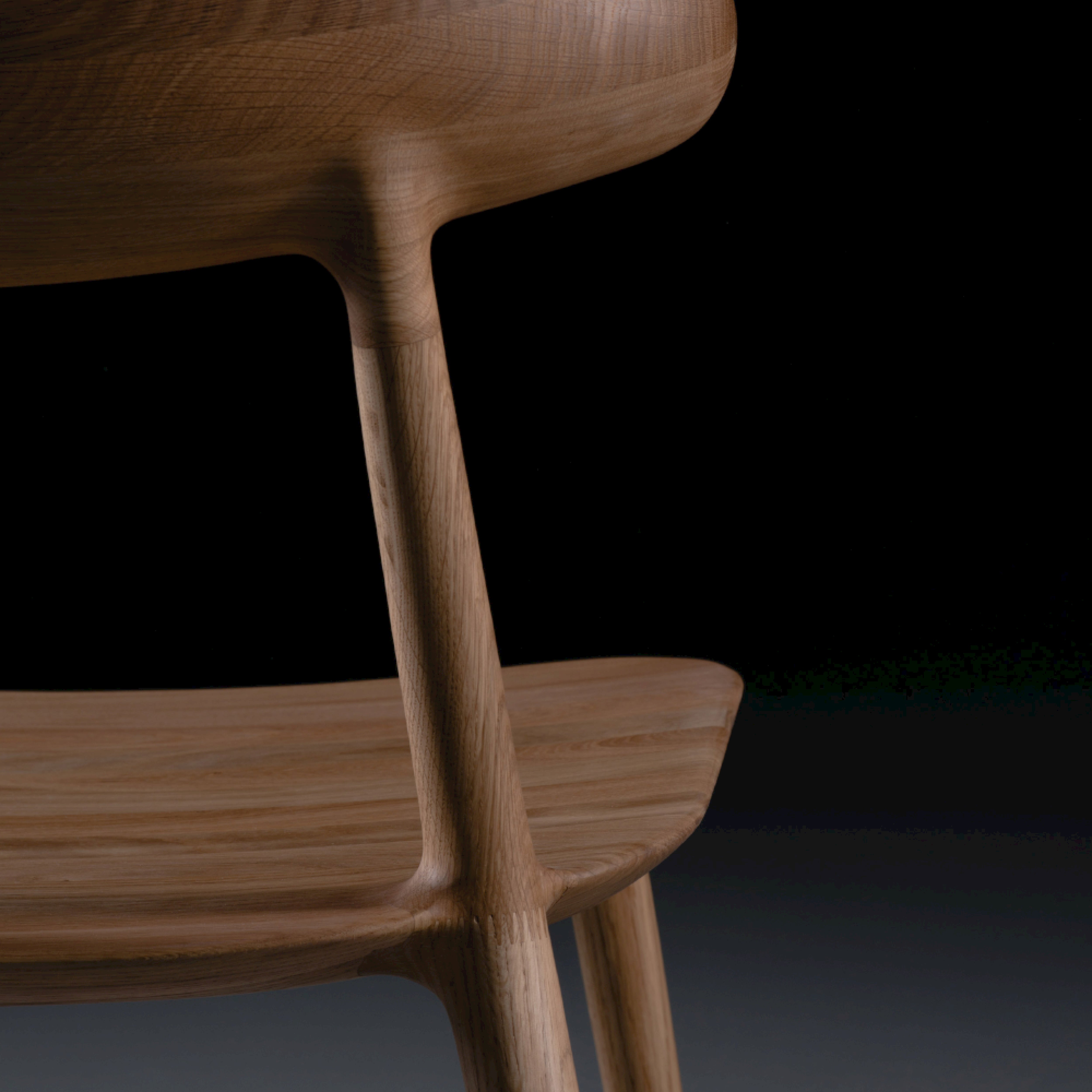 Close-up of the Artisan WU Chair showcasing its smooth, curved lines and minimalist design. Crafted from environmentally-friendly materials, a dark background highlights the chairs natural wood texture and craftsmanship.
