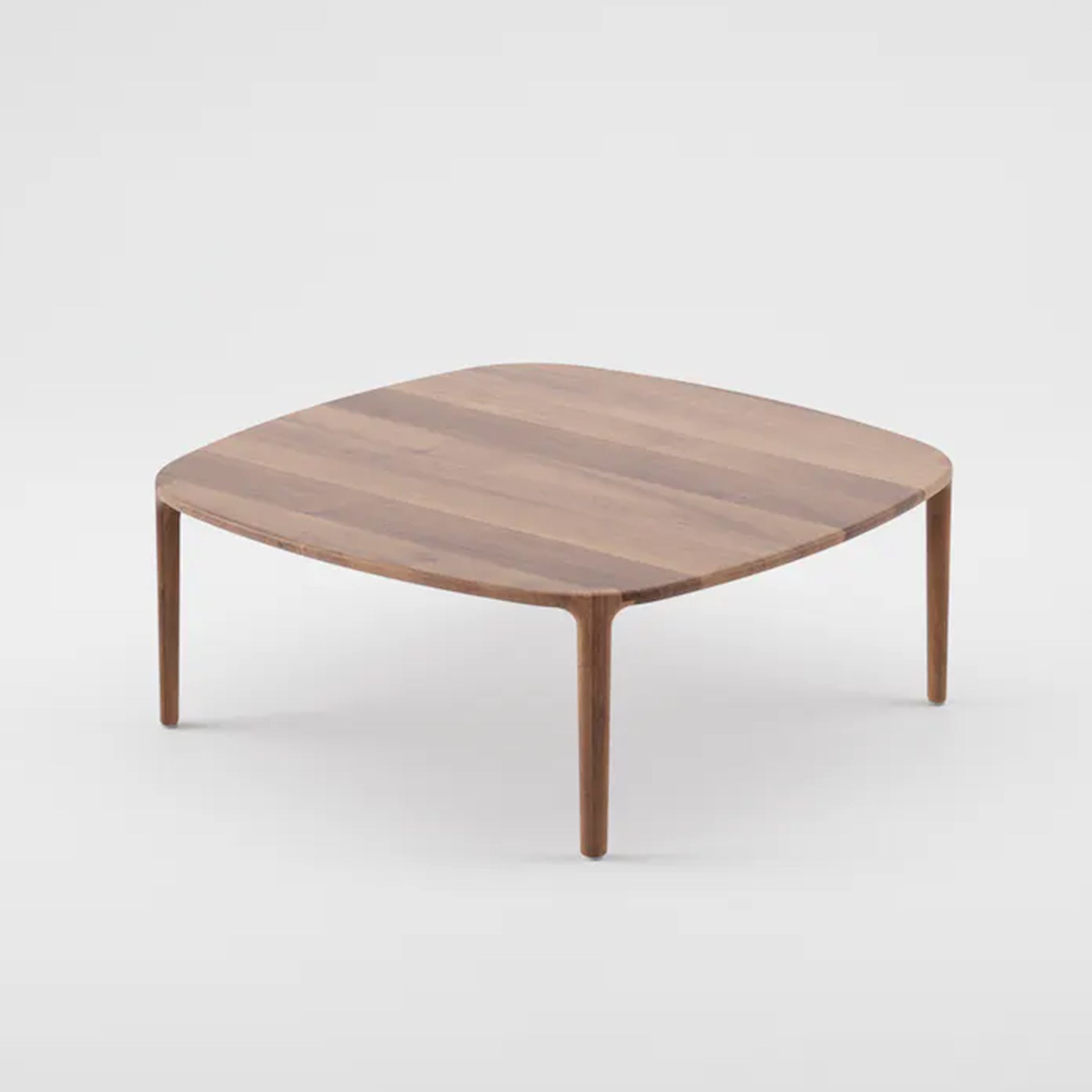 The WU Coffee Table by Artisan features a square, rounded-edge top with four slender legs. Made from solid wood, it flaunts natural grain patterns and uses eco-friendly materials and oils for a minimalist, modern look against a plain white backdrop.