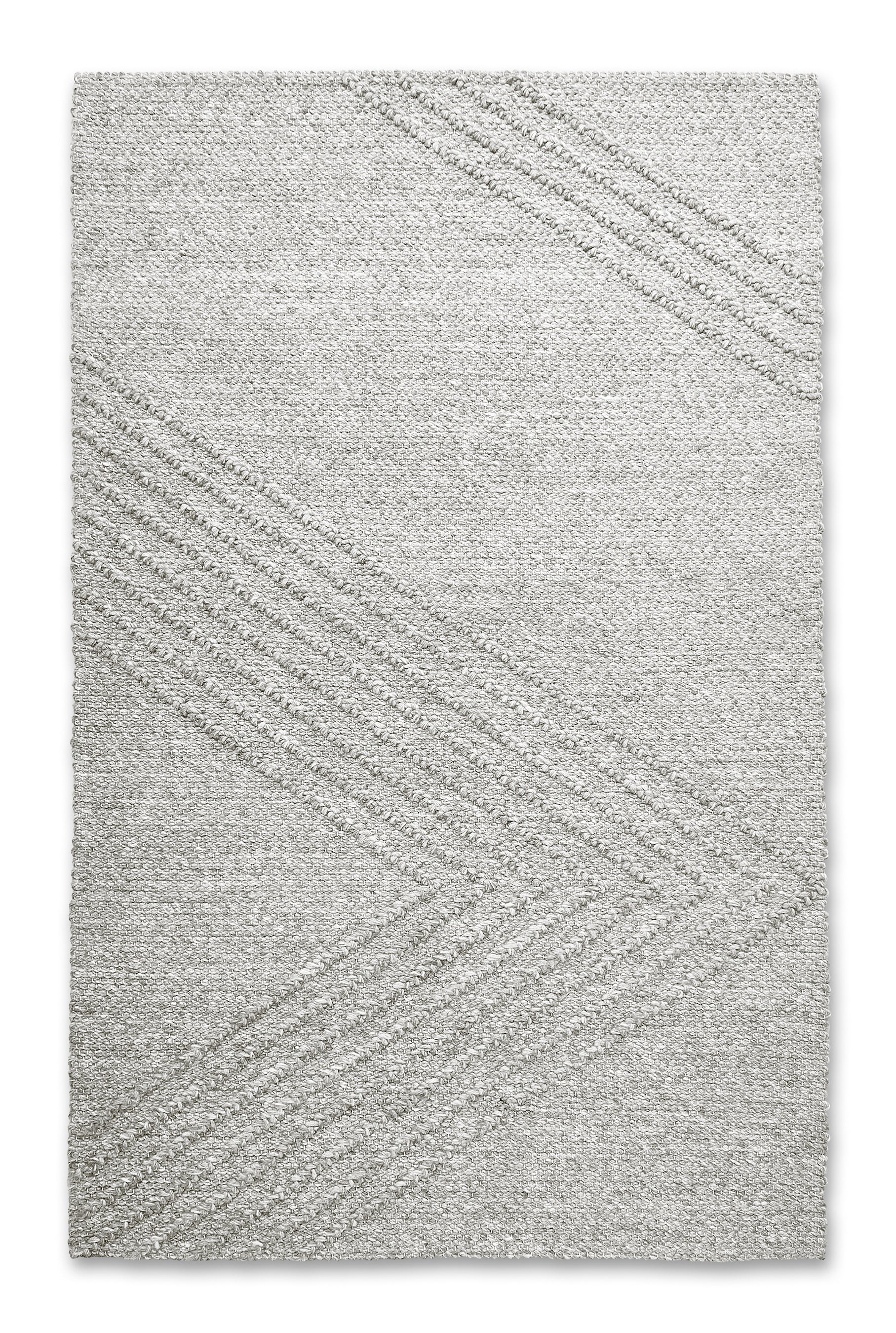 The Avro Rug by Gus Modern is a light gray, minimalist hand-knotted New Zealand wool rug featuring subtle diagonal lines that form large chevron shapes, lending a modern and sophisticated touch to any space.