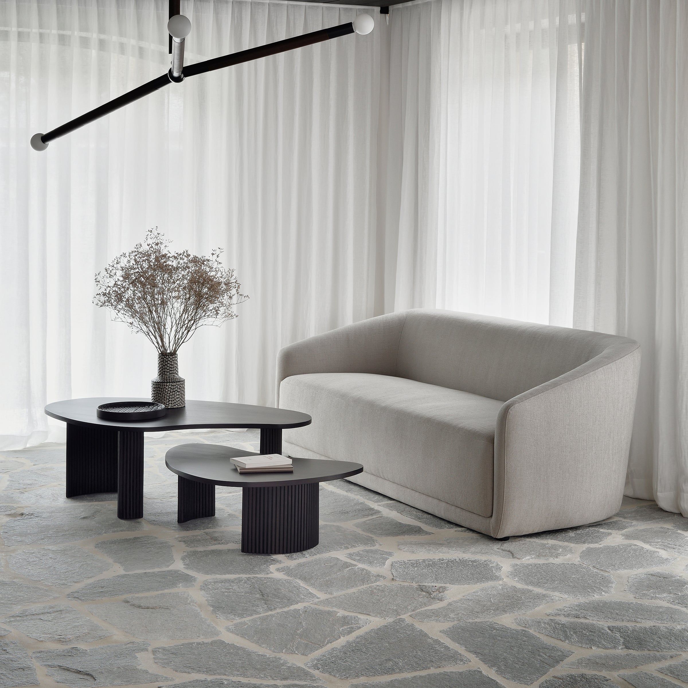 Boomerang Coffee Table in dark varnished mahogany with sleek curves, paired with modern sofa in bright living room.