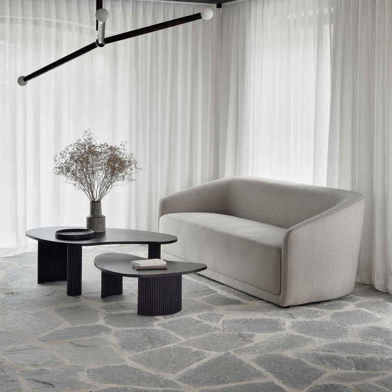 Boomerang Coffee Table in dark varnished mahogany with sleek curves, paired with modern sofa in bright living room.