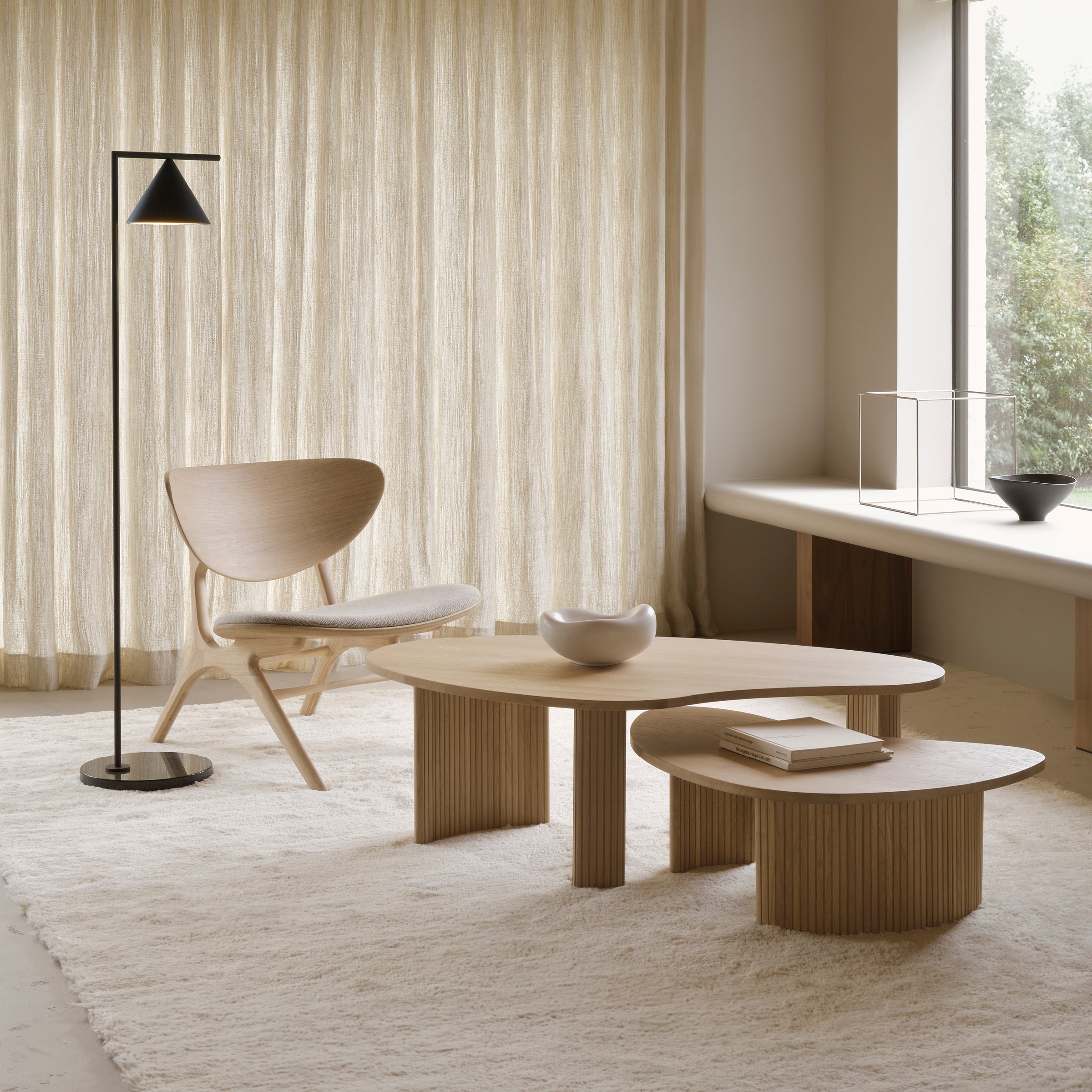 Boomerang Coffee Table in oak with modern design, paired with chair and floor lamp in minimalist living room.